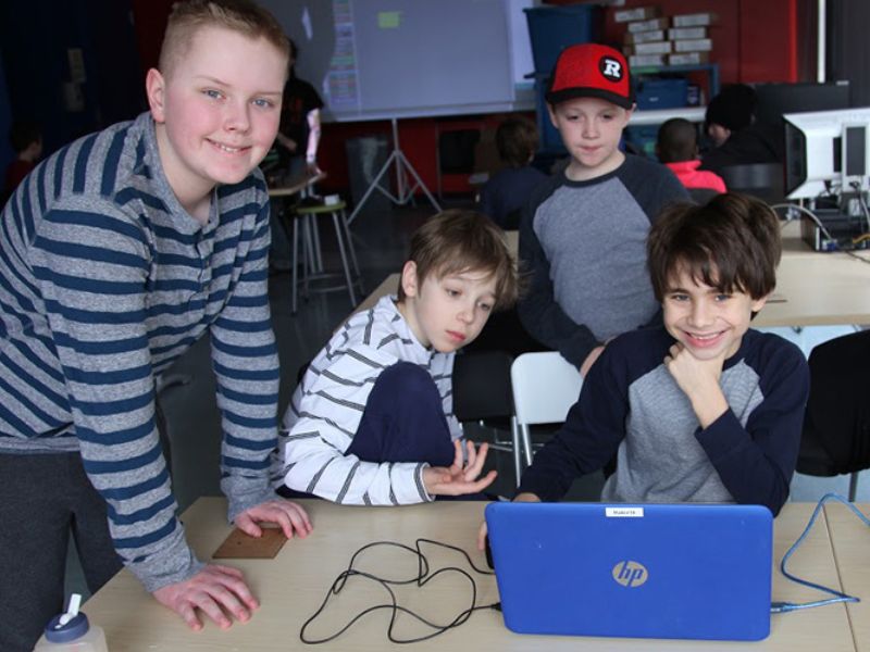 Group of student around a blue laptop.